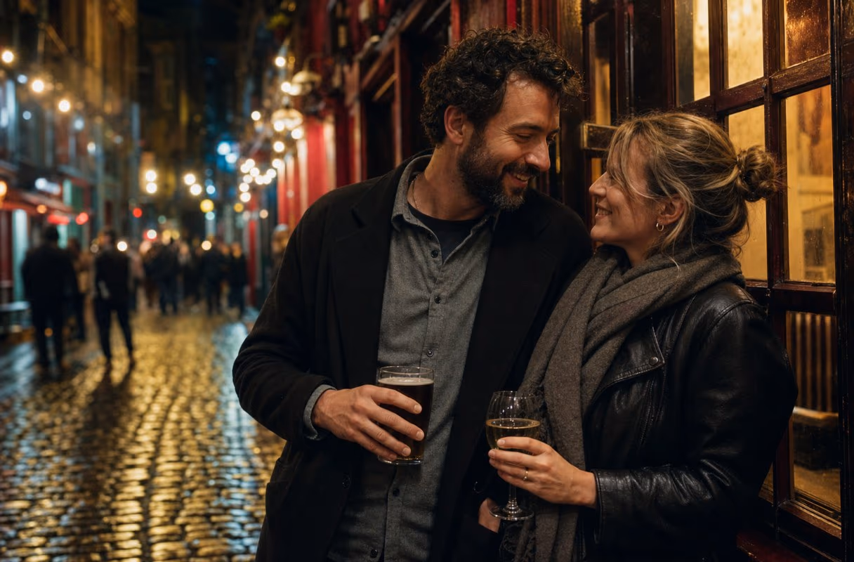 Temple Bar nach Einbruch der Dunkelheit — wo Dublin aufhört, zurückhaltend zu sein Ein Paar eng beieinander an einer gepflasterten Gasse in Temple Bar bei Nacht