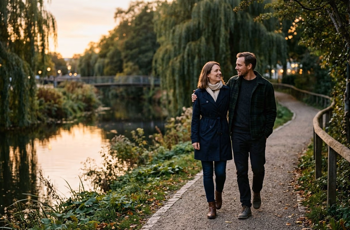 Das Flussufer in Odense in der Abenddämmerung — still und ohne Eile Ein Paar geht dicht beieinander den grünen Uferweg des Flusses in Odense entlang in der Abenddämmerung