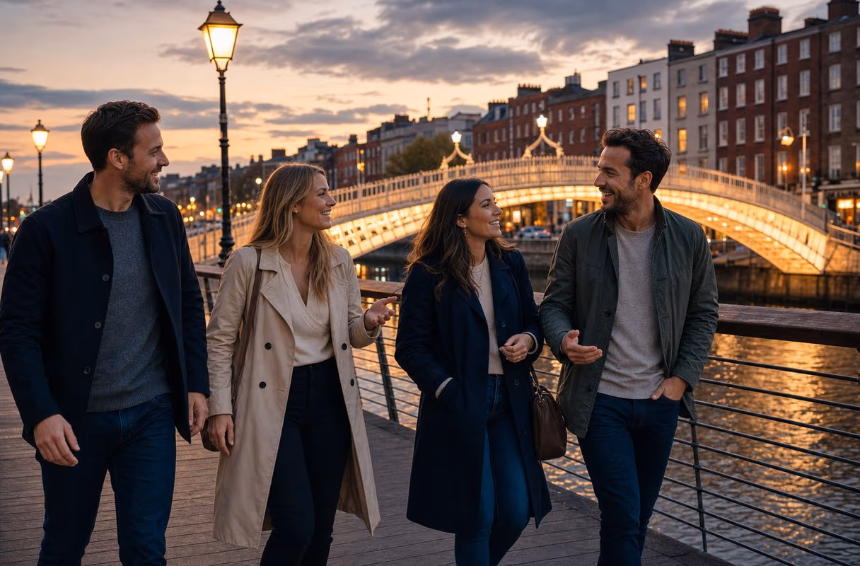 La promenade de la Liffey au crépuscule — le versant décontracté de la région Quatre personnes marchant sur la promenade de la Liffey à Dublin au crépuscule, le pont Ha'penny illuminé derrière